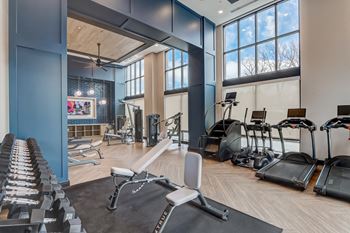 A gym with weights and exercise machines and windows
